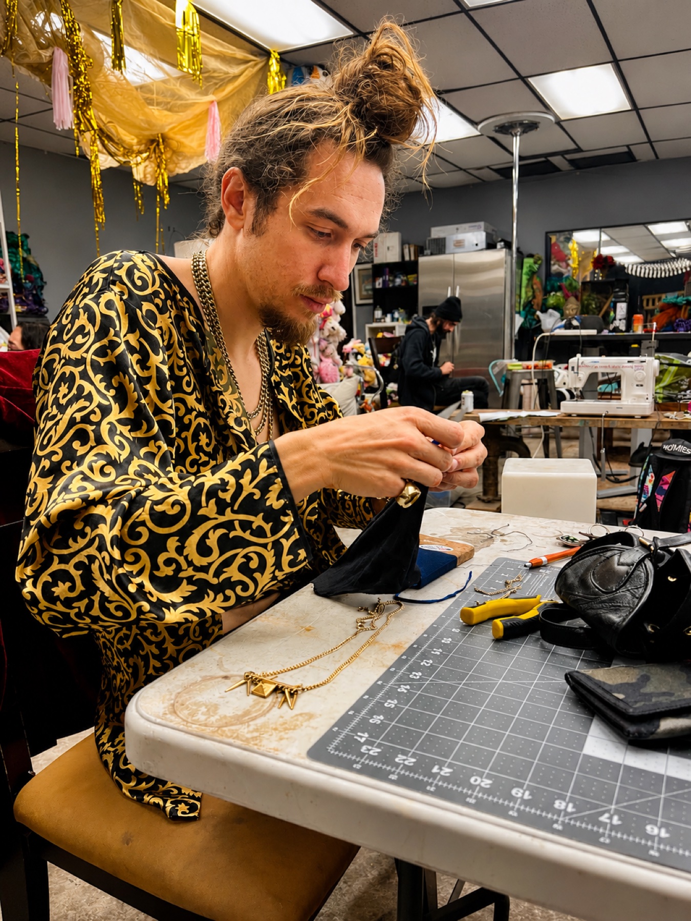 Art Night · hand-stitching at the cutting mat in a gold brocade robe