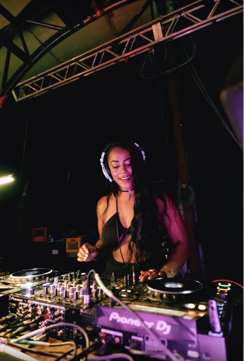 A DJ smiling mid-set behind the Pioneer decks
