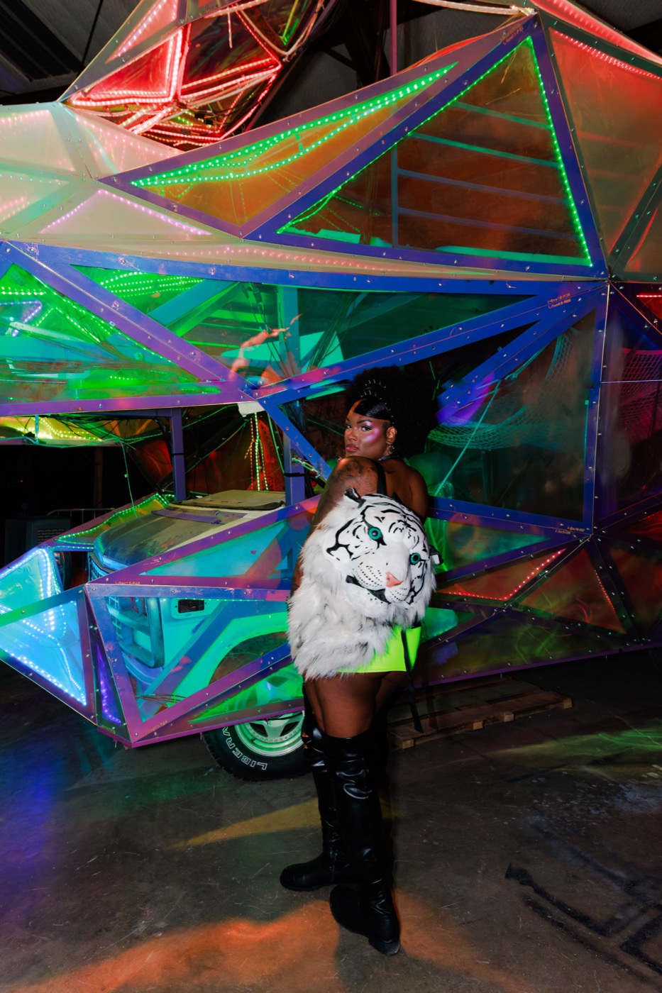 A dancer posing in front of the mirrored geodesic car sculpture at Babestock