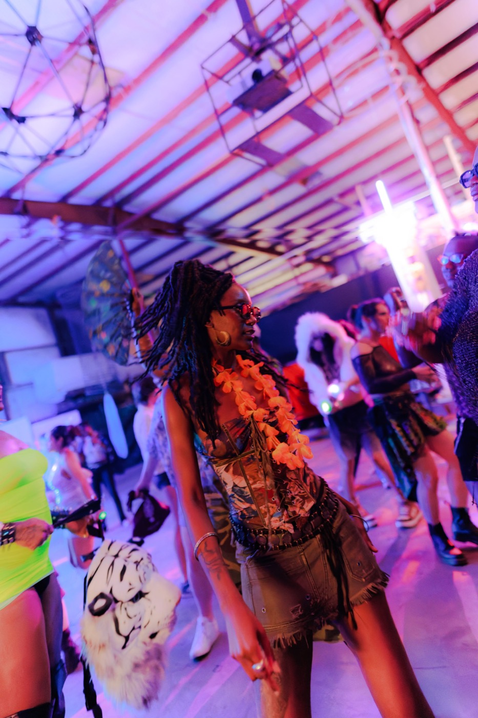 Babestock Rave · a dancer in an orange lei moving through the crowd under violet light